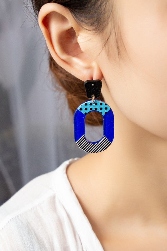 yellow, blue and black cutout oval hoop earrings with glitter background and color blocks