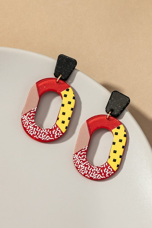 red, yellow and black cutout oval hoop earrings with glitter background and color blocks